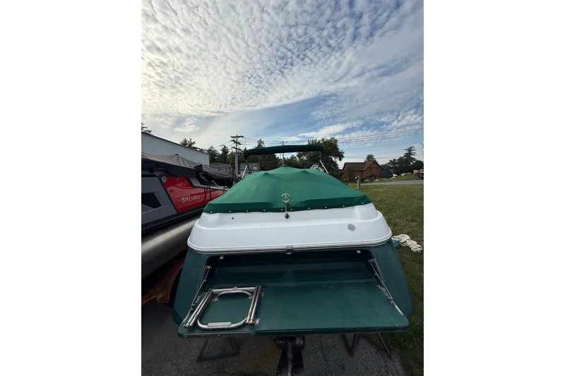 Slide: The Image of 1996 Cobalt 272 boat with green cover, parked outdoors under a cloudy sky. - 38