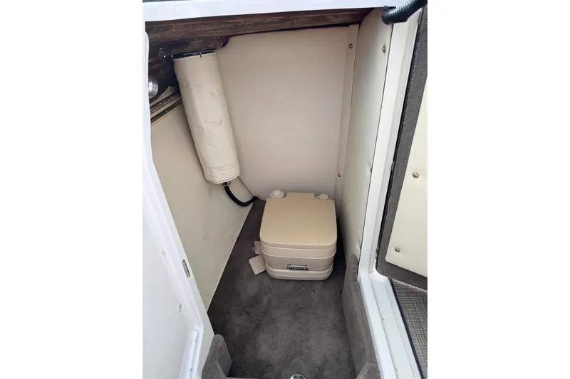 Slide: The Image of Compact marine toilet in 1996 Cobalt 272 boat cabin, featuring carpeted flooring and storage. - 23