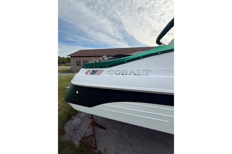 Slide: The Image of 1996 Cobalt 272 boat on stand, white and green exterior, clear sky background. - 33