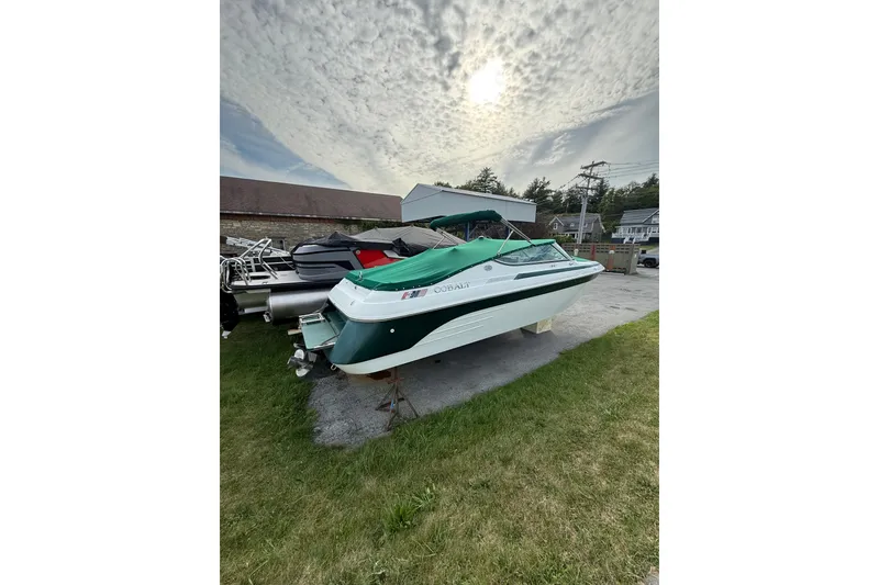 Slide: The Image of 1996 Cobalt 272 boat with green cover, parked outdoors under cloudy sky. - 30