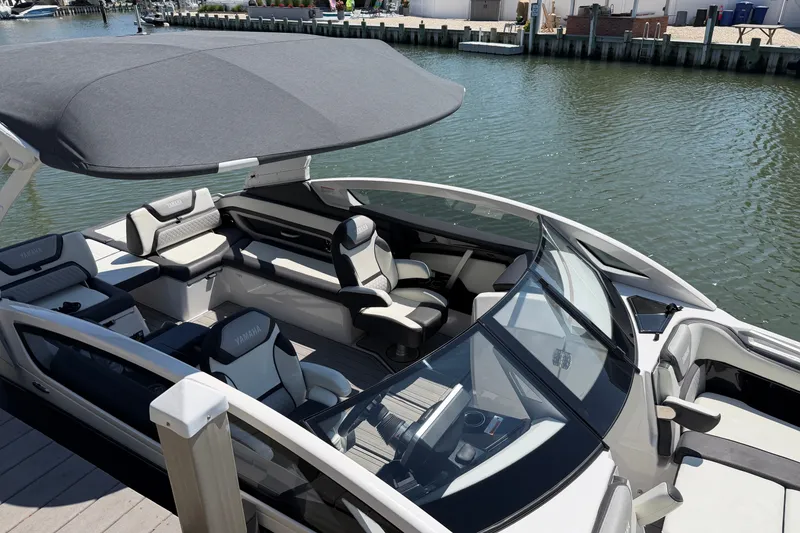 Slide: The Image of 2023 Yamaha Boats 275SE with sleek interior and canopy, docked by the water. - 26