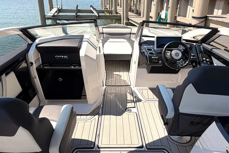 Slide: The Image of 2023 Yamaha Boats 275SE interior, featuring sleek design and modern dashboard at a marina. - 10
