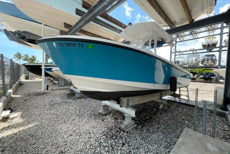 Slide: The Image of 2007 Edgewater 245CC boat in dry storage, vibrant blue hull, sunny day. - 23