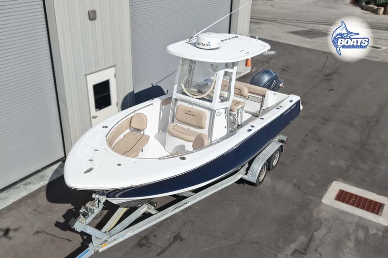 Slide: The Image of 2019 Sportsman Open 232 Center Console boat on trailer, parked outside a building. - 1