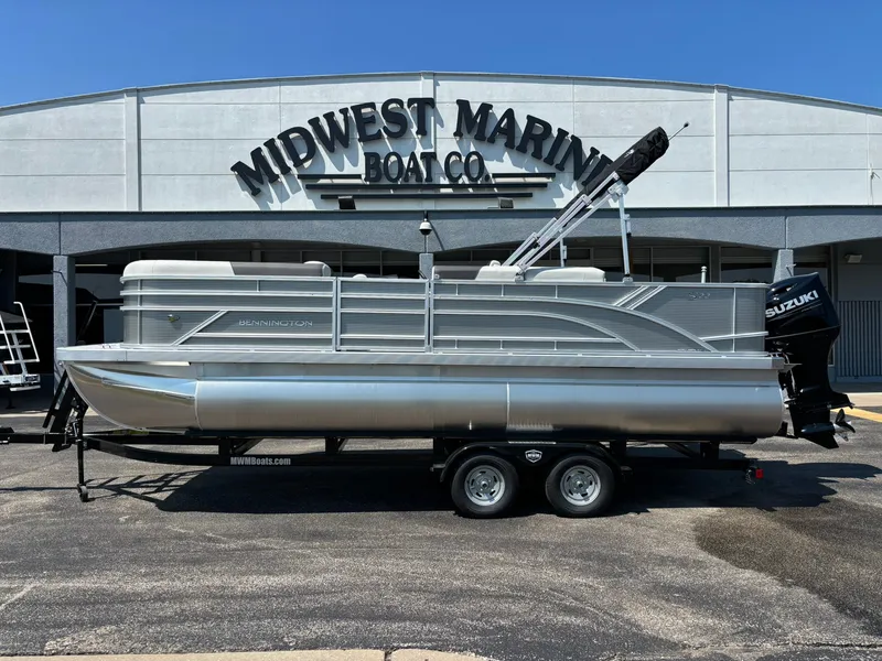 The Image of The image shows a Bennington 22 S1FNC SPS pontoon boat on a trailer in front of a building labeled "Midwest Marine Boat Co." - 1
