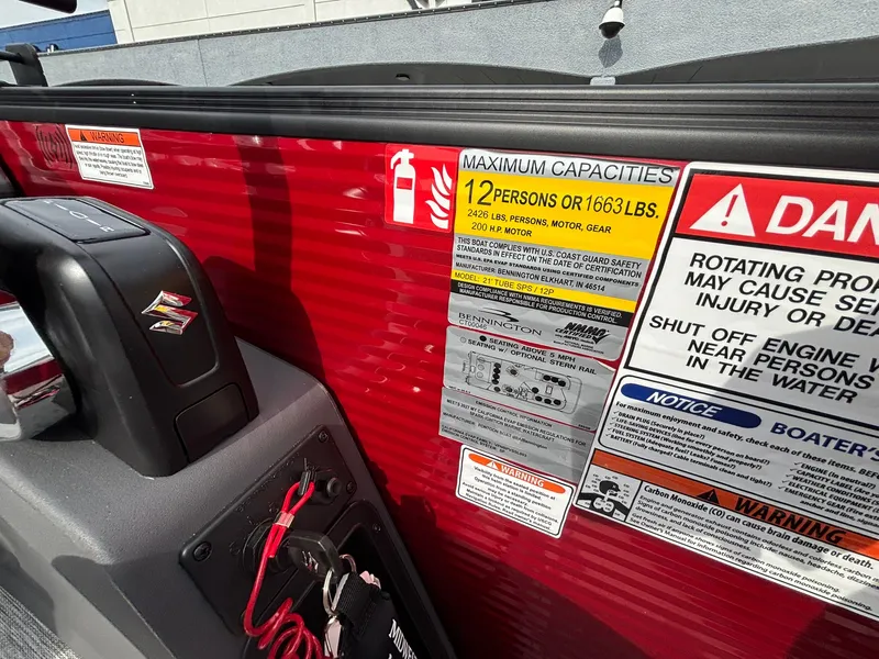 Slide: The Image of Close-up of a boat area with safety and capacity notices. Red surface with Suzuki logo. - 24