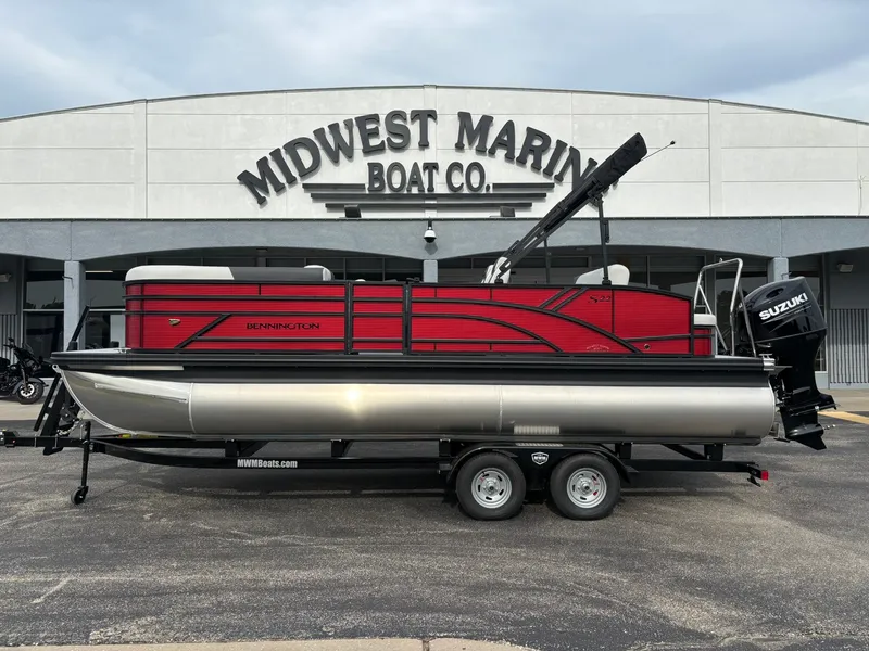 The Image of A red Bennington 21 S1SB SPS pontoon boat on a trailer in front of a Midwest Marine Boat Co. building. - 1
