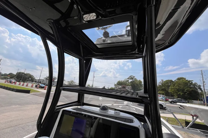 Slide: The Image of 2022 Tidewater 2500 Carolina Bay boat interior with electronics and T-top under blue sky. - 9