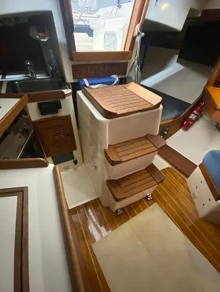 Slide: The Image of The interior of a 1992 Tartan 3100 features a wooden staircase and a cozy cabin. - 9