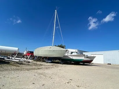 Slide: The Image of A 1992 Tartan 3100 is on a dry dock next to other boats under a clear blue sky. - 15