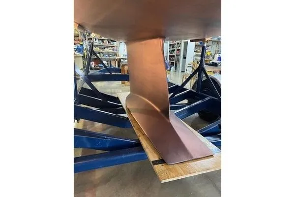 Slide: The Image of The keel of a 1992 Tartan 3100 on a blue boat trailer in a workshop. - 13