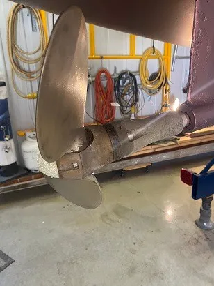 Slide: The Image of A propeller of a 1992 Tartan 3100 boat in a workshop with tools in the background. - 12
