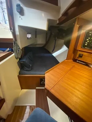 Slide: The Image of Interior of a 1992 Tartan 3100 with a wooden table and sleeping area. - 6
