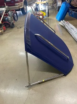 Slide: The Image of A blue bimini top with a stainless steel frame stands on a concrete floor in a workshop. - 16