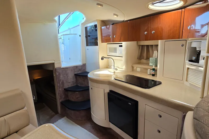 Slide: The Image of Interior of a 2001 Monterey 322 Cruiser yacht, featuring a compact kitchen and cozy seating area. - 21