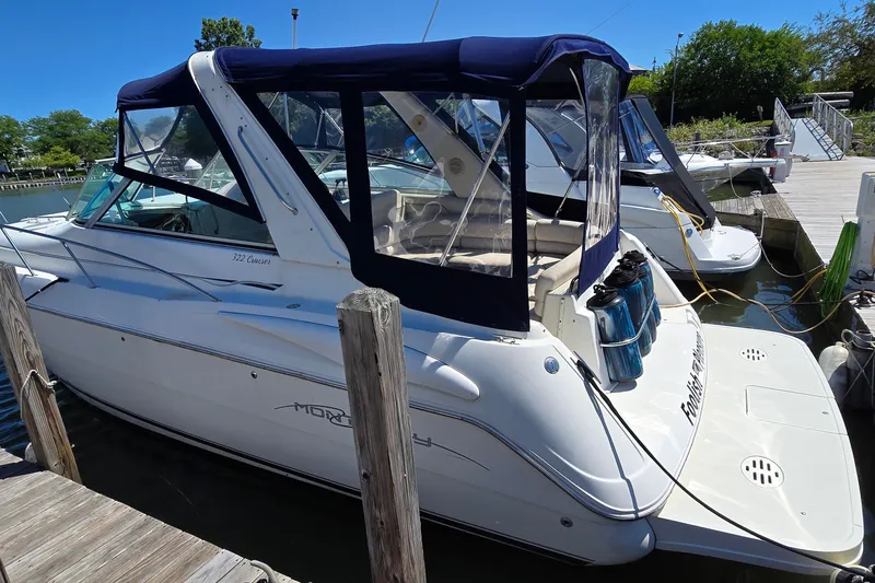 Slide: The Image of 2001 Monterey 322 Cruiser docked at marina, featuring blue canopy and sleek design. - 2