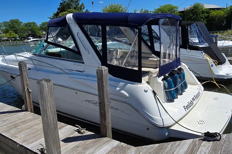 The Image of 2001 Monterey 322 Cruiser docked, featuring blue canopy and sleek design. - 1