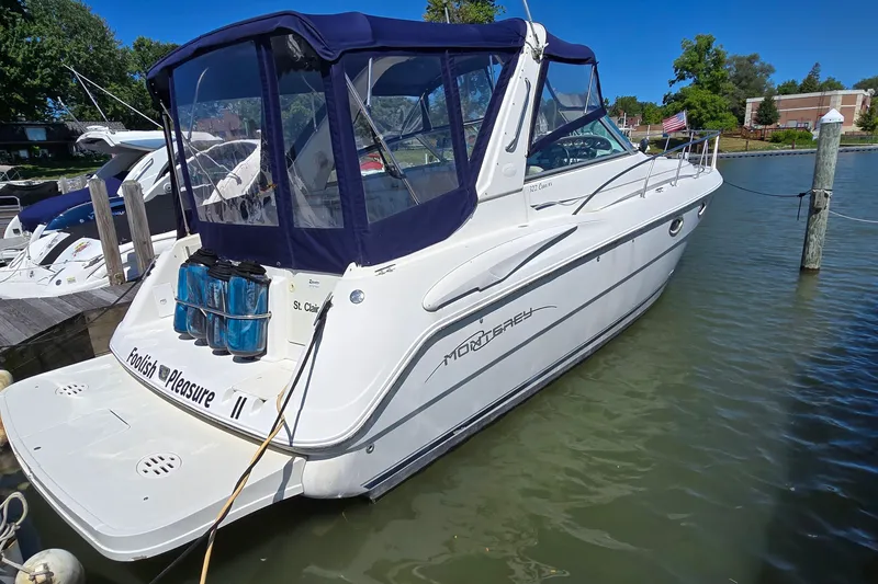 Slide: The Image of 2001 Monterey 322 Cruiser docked, featuring a sleek design and blue canopy. - 4