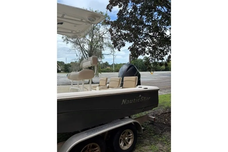 Slide: The Image of 2017 Nautistar 227 XTS boat on trailer, parked outdoors with trees in background. - 8