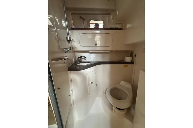 Slide: The Image of 2005 Grady-White Express 330 boat bathroom with sink, toilet, and storage cabinets. - 27