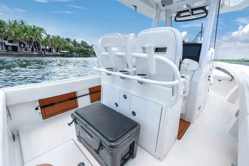 Slide: The Image of 2023 Regulator 28 Forward Seating boat interior with rod holders and cooler, near tropical shoreline. - 32