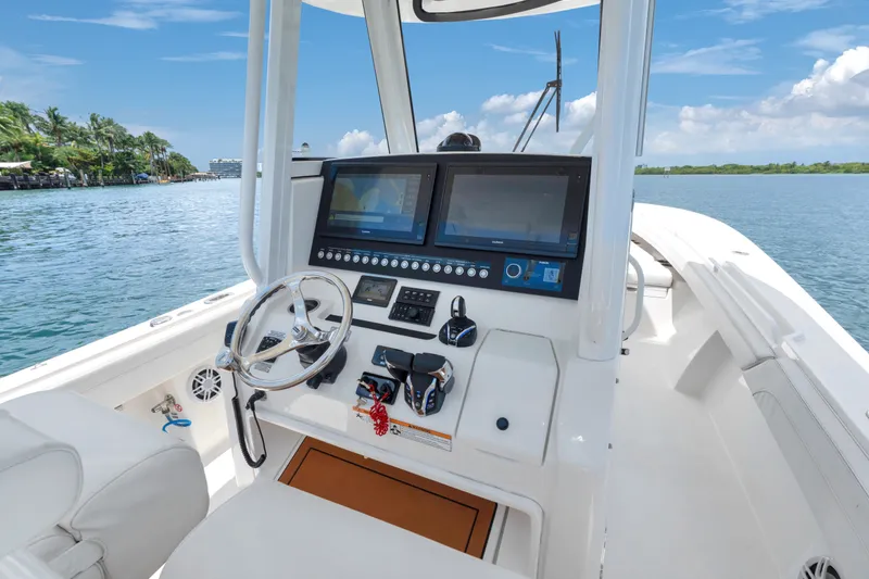 Slide: The Image of 2023 Regulator 28 Forward Seating boat cockpit with dual screens and steering wheel on open water. - 19