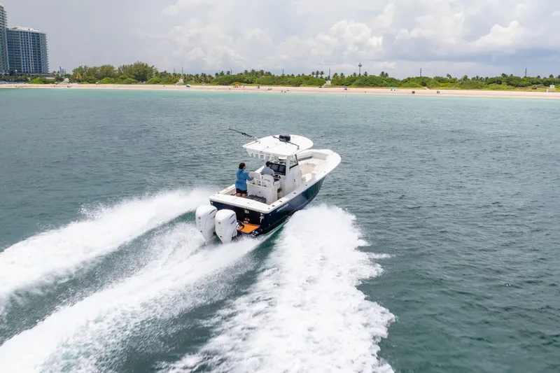 Slide: The Image of 2023 Regulator 28 Forward Seating boat cruising near a sandy shoreline. - 2