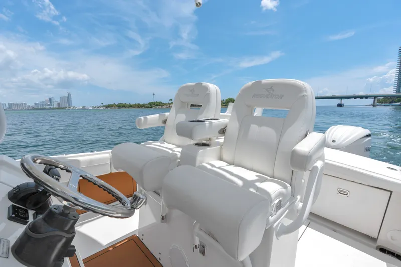 Slide: The Image of 2023 Regulator 28 Forward Seating boat interior with white captain chairs on a sunny day. - 28