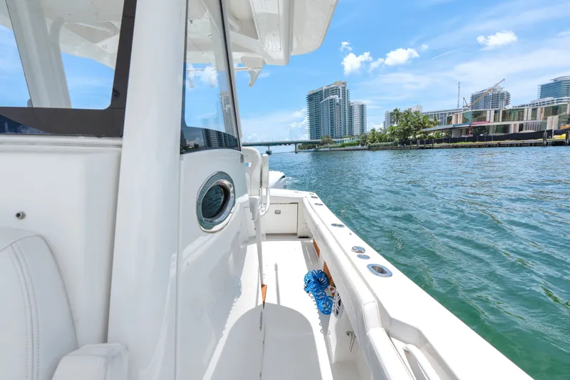 Slide: The Image of 2023 Regulator 28 Forward Seating boat cruising near waterfront cityscape. - 35
