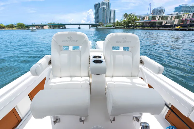 Slide: The Image of 2023 Regulator 28 Forward Seating boat with luxurious white seats on a scenic waterway. - 29