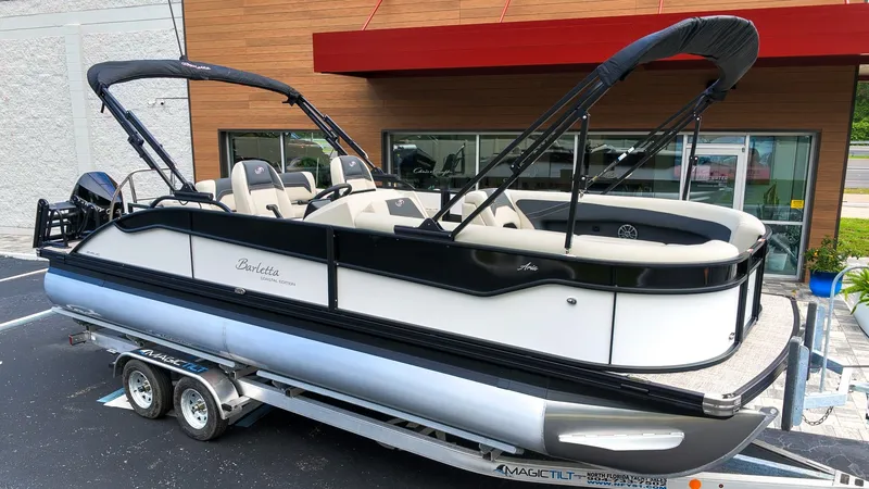 The Image of A sleek pontoon boat with black and white design, parked on a trailer in front of a building. - 1
