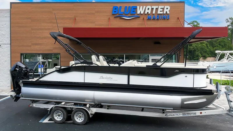 Slide: The Image of Barletta Aria 24UC pontoon boat on a trailer in front of a marine store. - 23