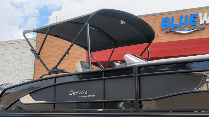 Slide: The Image of The image shows a Barletta Lusso 25UE pontoon boat with a black canopy. - 33
