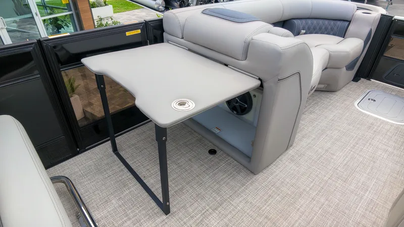 Slide: The Image of The image shows the interior of a Barletta Lusso 25UE boat with a folding table and cushioned seating. - 22