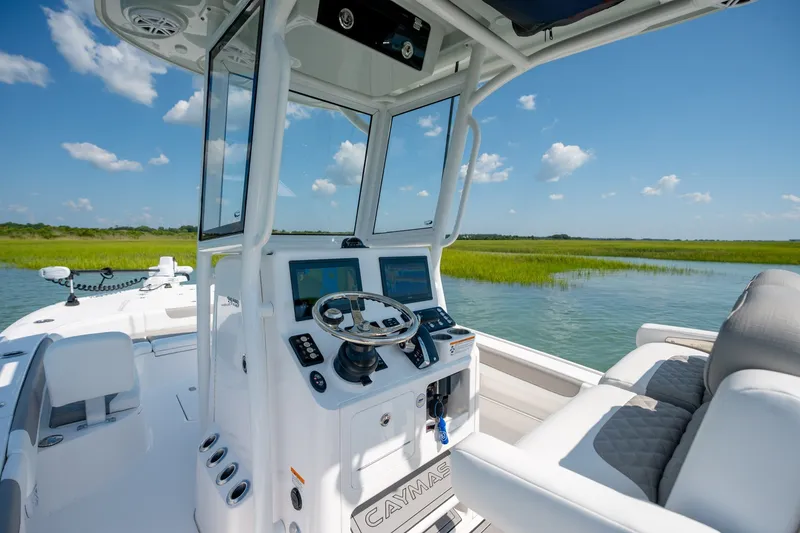 Slide: The Image of 2025 Caymas 26 HB boat interior with modern controls, cruising on a serene waterway. - 15