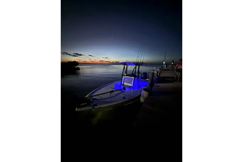 Slide: The Image of 2025 Sea Hunt BX22BR boat docked at sunset with blue interior lights. - 6