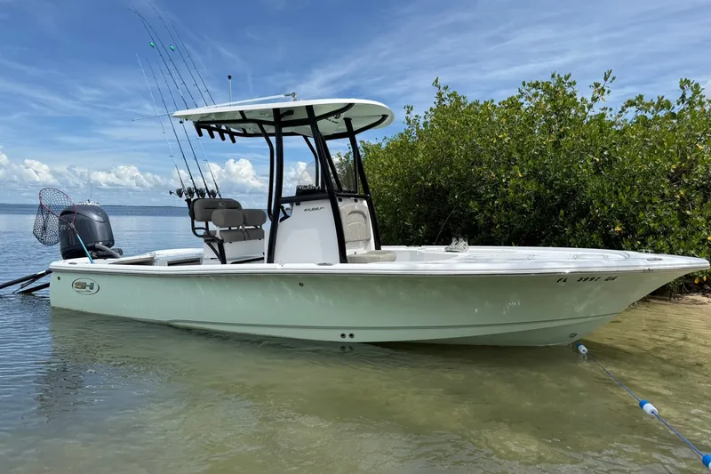 The Image of 2025 Sea Hunt BX22BR boat docked on a sandy shore with fishing gear. - 0