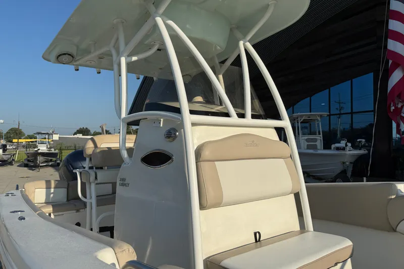 Slide: The Image of 2016 NauticStar 2302 Legacy boat with beige seating and T-top, docked outdoors. - 19