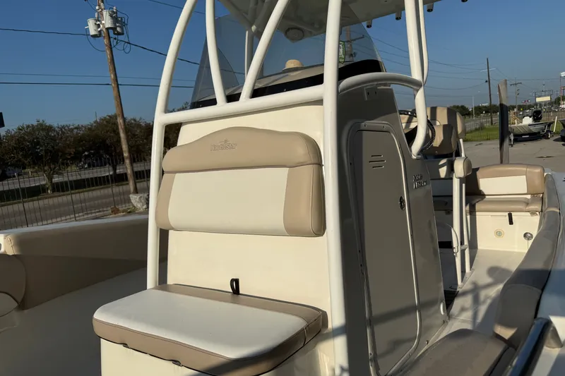 Slide: The Image of 2016 NauticStar 2302 Legacy boat interior with seating and console, parked outdoors. - 18