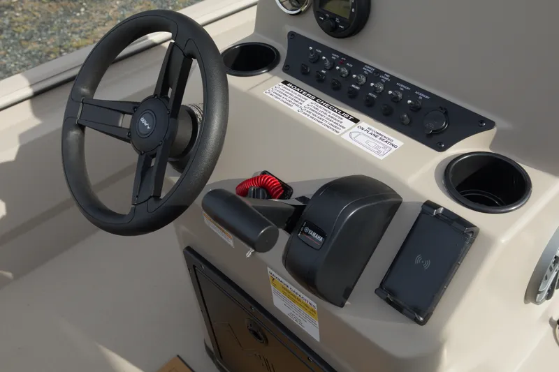 Slide: The Image of Steering console of 2027 Avid 20 Rogue CC boat with controls and cup holders. - 19