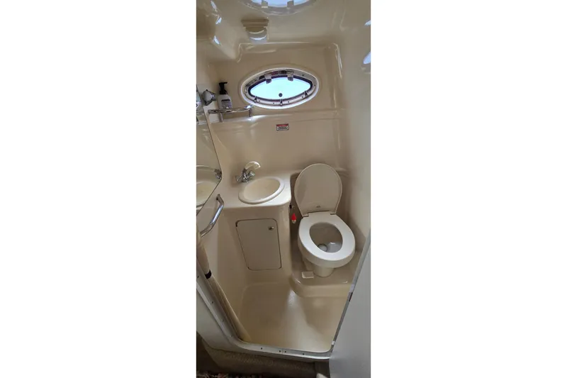 Slide: The Image of 2003 Sea Ray Sundancer 260 boat bathroom with toilet, sink, and porthole window. - 24