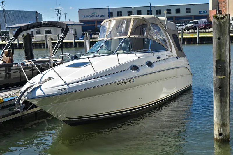 The Image of 2003 Sea Ray Sundancer 260 docked at marina, featuring sleek design and beige canopy. - 1