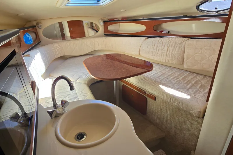 Slide: The Image of Interior of 2003 Sea Ray Sundancer 260, featuring cozy seating and compact kitchenette. - 26