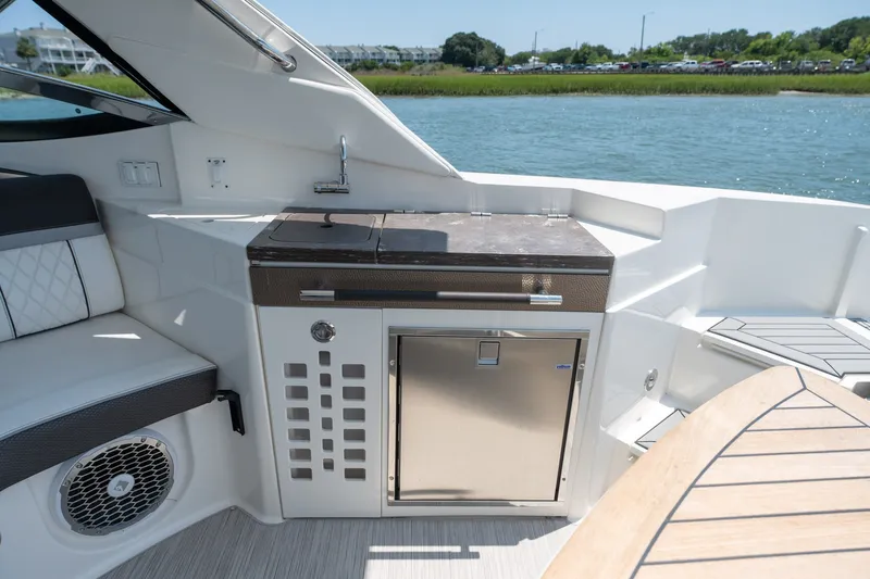 Slide: The Image of Outdoor kitchenette on a 2017 Sea Ray SLX 350 boat, featuring a grill and seating area. - 37