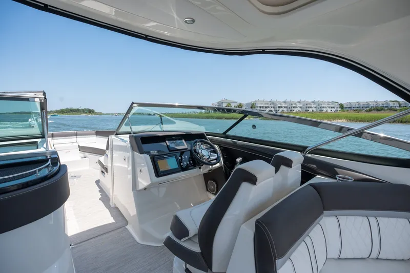 Slide: The Image of 2017 Sea Ray SLX 350 boat interior with helm, overlooking scenic waterfront. - 19
