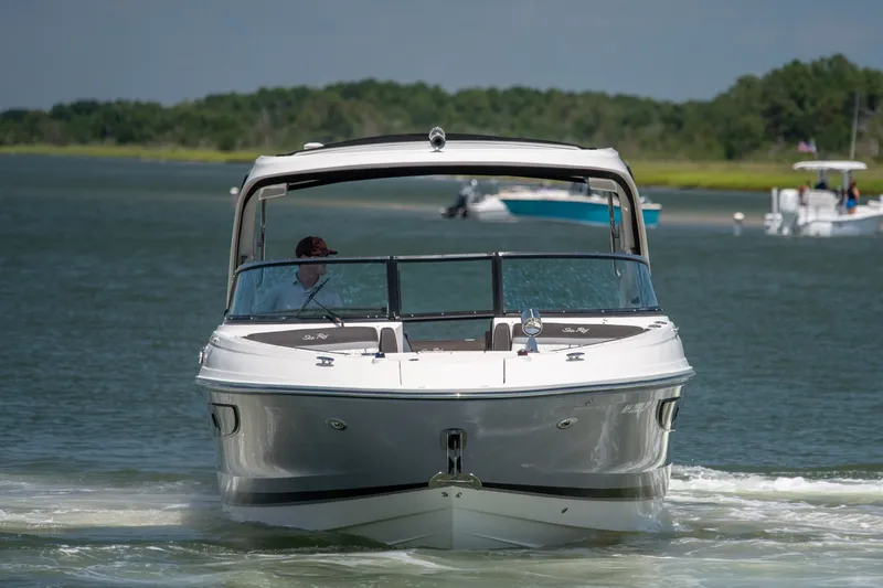 Slide: The Image of 2017 Sea Ray SLX 350 boat cruising on a calm lake with lush green shoreline. - 7