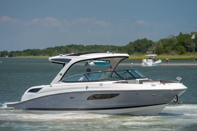 Slide: The Image of 2017 Sea Ray SLX 350 cruising on a serene lake with lush green shoreline. - 8