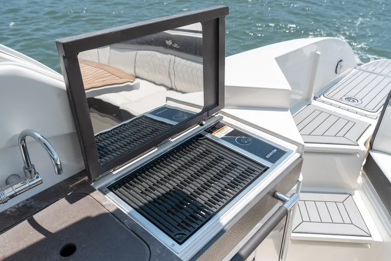 Slide: The Image of Outdoor grill on 2017 Sea Ray SLX 350 boat, with sleek seating and water backdrop. - 36