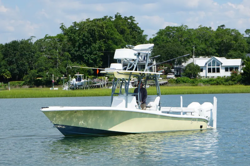 The Image of 2020 Yellowfin 26 Hybrid boat cruising on a calm lake with lush greenery in the background. - 1