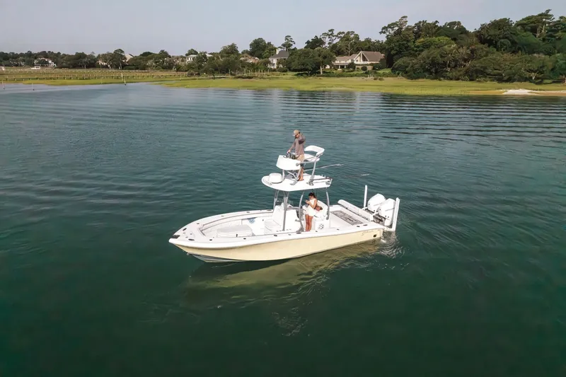 The Image of 2020 Yellowfin 26 Hybrid boat cruising on calm waters near a lush shoreline. - 2